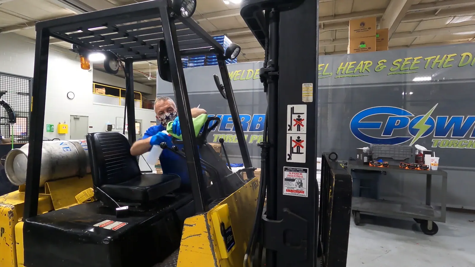 Technician wiping surfaces on a forklift in a commercial workspace